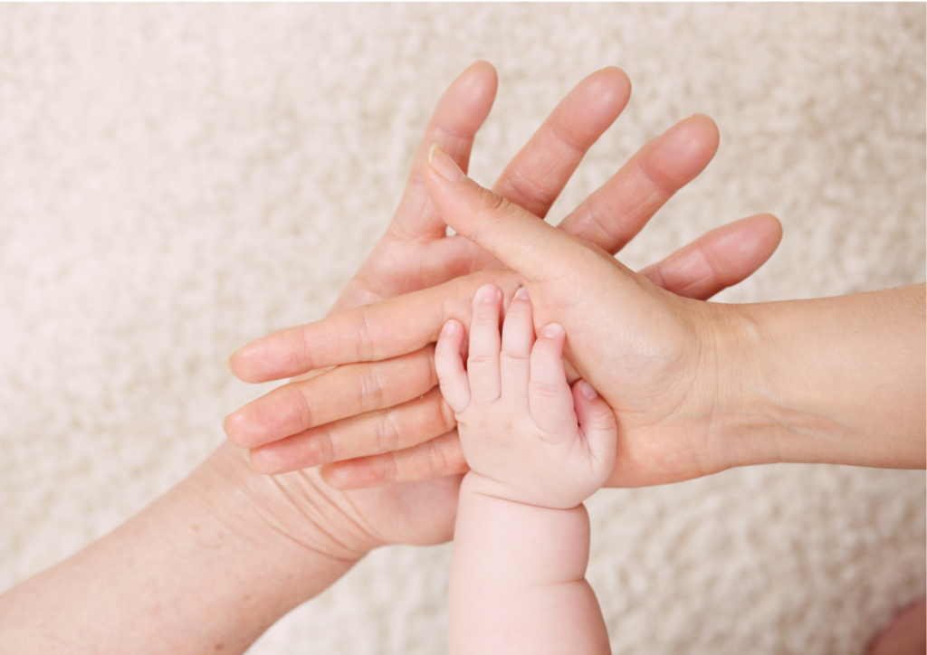 3 mains posées l'une sur l'autre : bébé, et 2 adultes